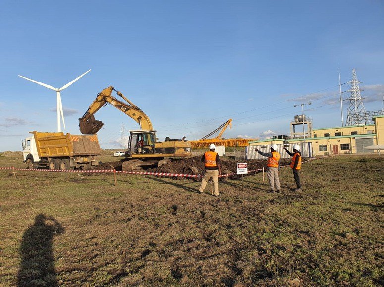 Excavator and crew working beside wind turbines