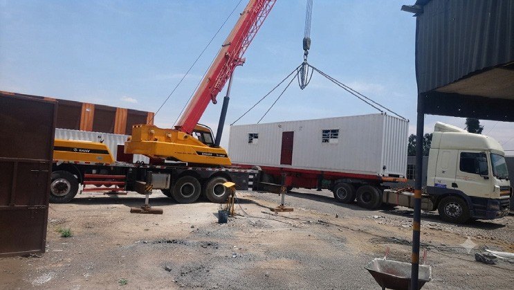 Crane lifting a modular office unit from a truck